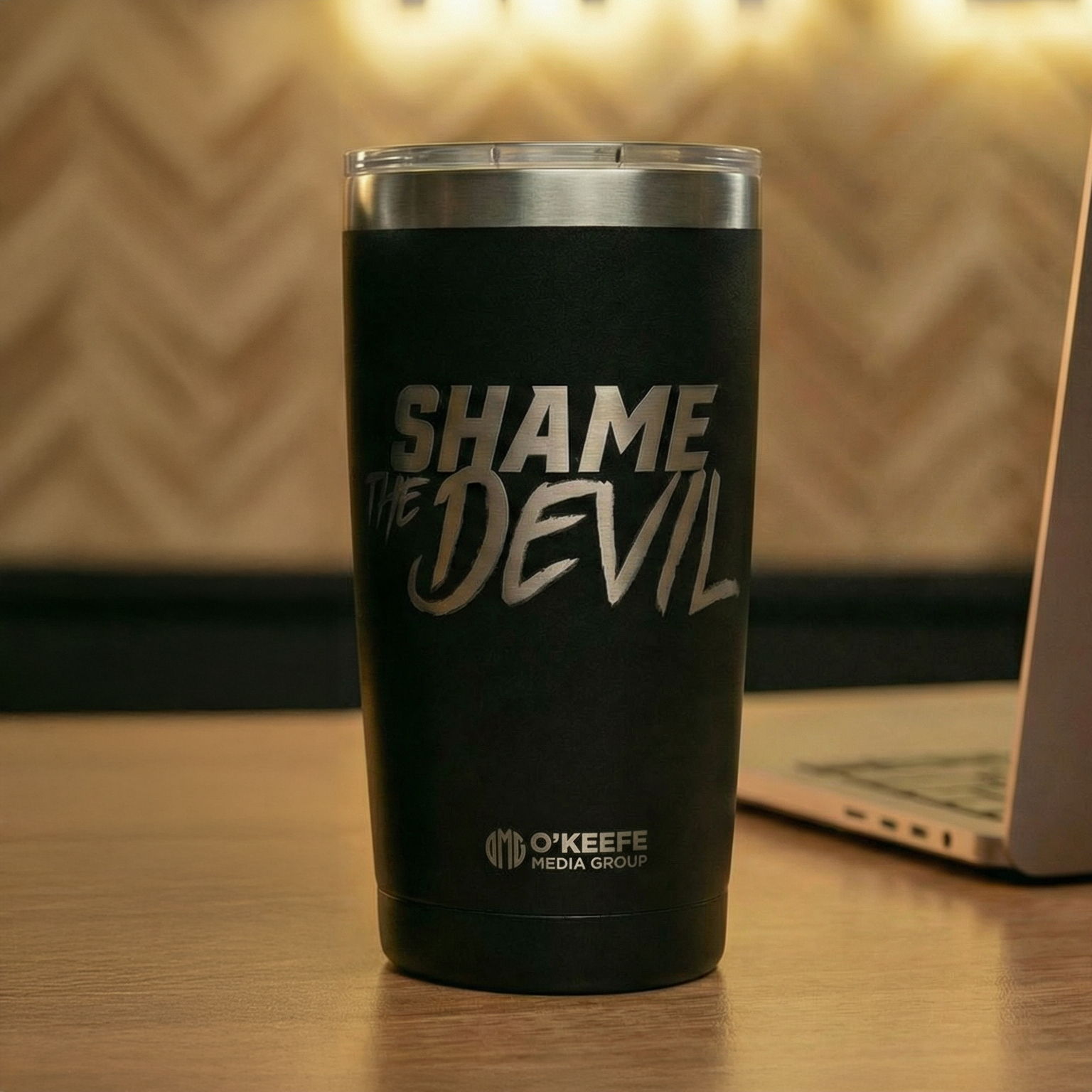 Black 20 oz stainless steel tumbler laser-engraved with "Shame the Devil" and the O'Keefe Media Group logo